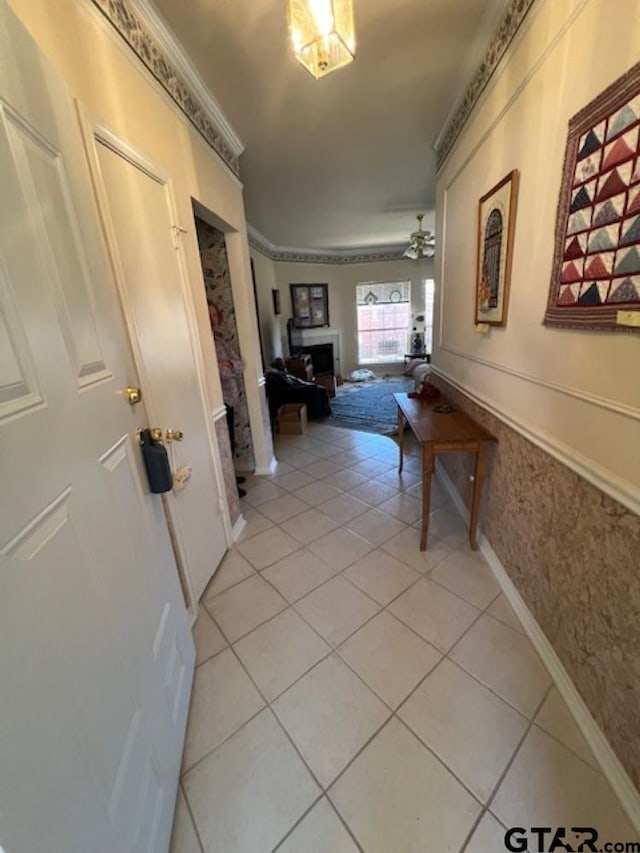 hallway with light tile patterned flooring, wainscoting, and crown molding