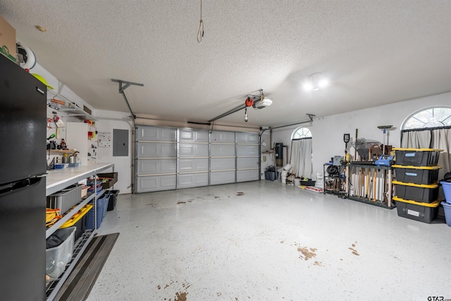 garage with electric panel, a garage door opener, and freestanding refrigerator