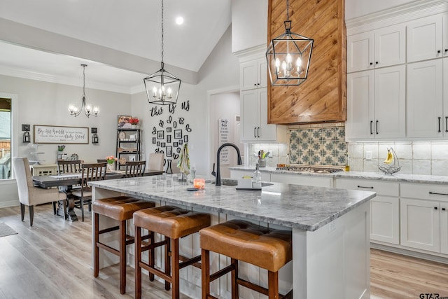 213 Serenity Dr, Bullard, TX 75757 - kitchen featuring a chandelier, backsplash, light wood finished floors, a center island with sink, and high vaulted ceiling