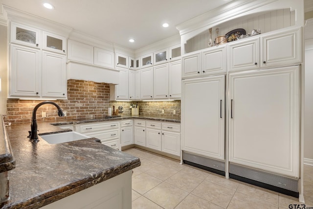 kitchen featuring black electric stovetop, a sink, dark stone countertops, white cabinetry, and backsplash