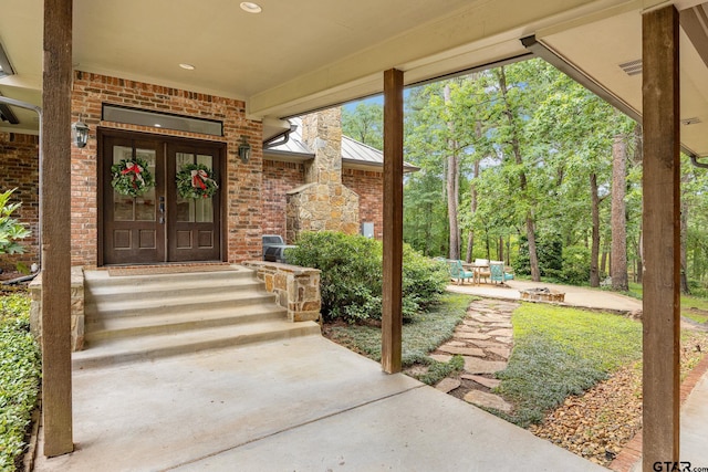 entrance to property with a standing seam roof, a patio area, french doors, and brick siding