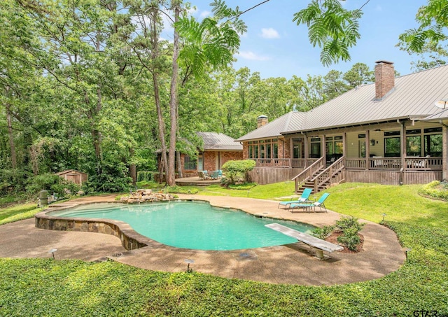 outdoor pool with a patio, an outbuilding, a lawn, a diving board, and a storage shed