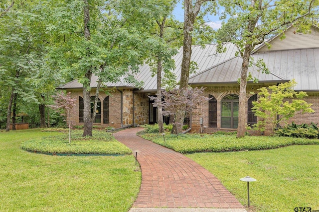 view of front of property featuring brick siding, a standing seam roof, metal roof, and a front yard