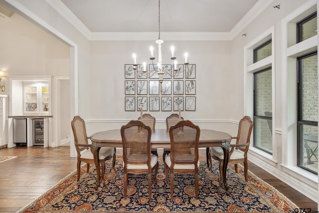 dining space featuring wine cooler, crown molding, a chandelier, and dark wood-type flooring