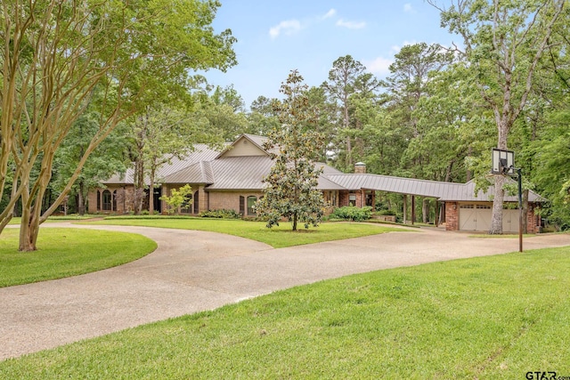 view of front of home with curved driveway, a chimney, and a front lawn