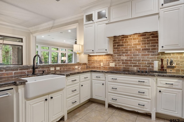 kitchen with a sink, decorative backsplash, white cabinetry, and ornamental molding