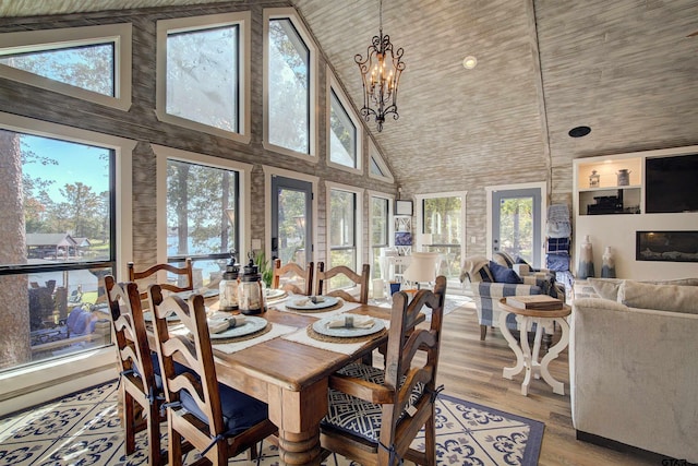 dining area featuring light wood-type flooring, a chandelier, and high vaulted ceiling