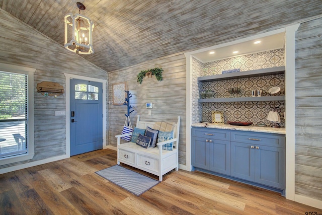 entryway with a healthy amount of sunlight, lofted ceiling, a notable chandelier, and light wood-type flooring