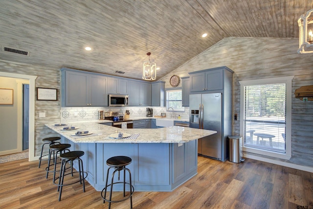 kitchen featuring stainless steel appliances, pendant lighting, wood ceiling, and kitchen peninsula