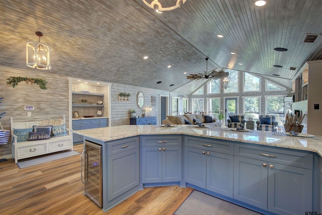 kitchen with lofted ceiling, decorative light fixtures, light hardwood / wood-style floors, and beverage cooler