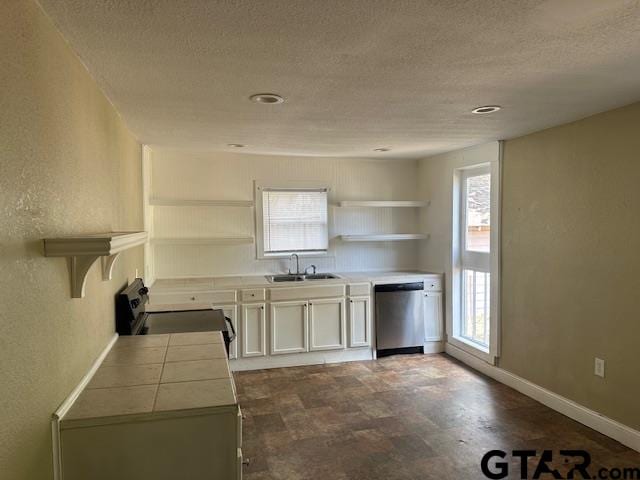 kitchen with tile counters, electric stove, white cabinets, sink, and stainless steel dishwasher