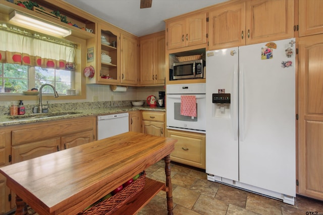 kitchen featuring white appliances, sink, and light stone counters