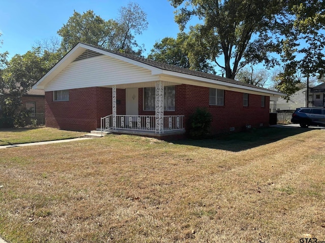 ranch-style house featuring covered porch and a front lawn