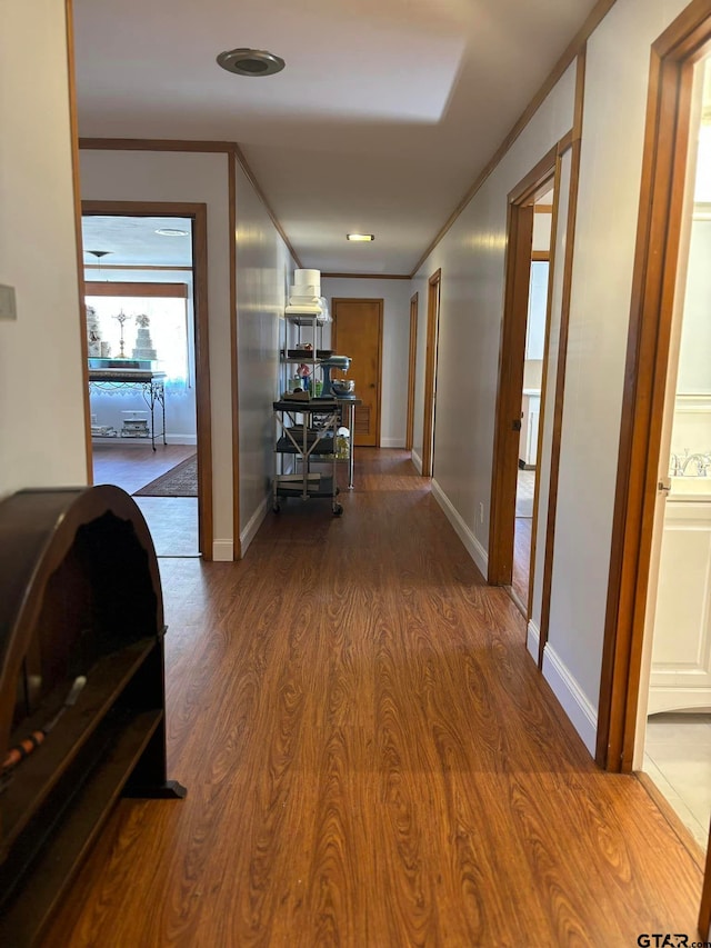 hallway with hardwood / wood-style floors and crown molding