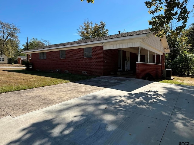 view of front of property with a front lawn, central AC unit, and a carport