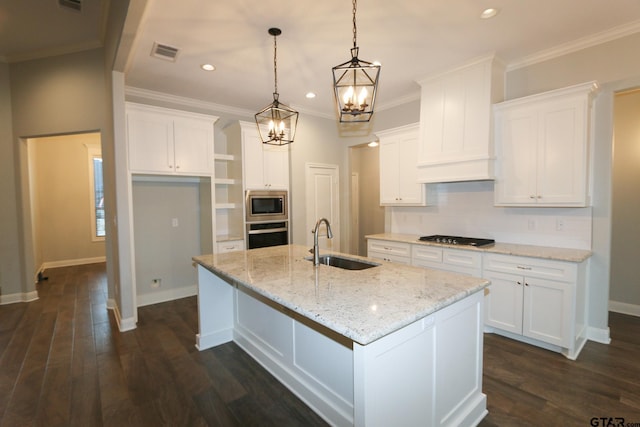 kitchen featuring sink, white cabinetry, hanging light fixtures, stainless steel appliances, and a center island with sink