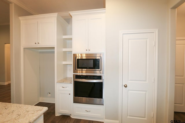 kitchen featuring appliances with stainless steel finishes, white cabinets, crown molding, light stone countertops, and dark wood-type flooring