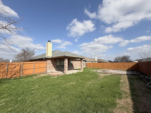 rear view of property featuring a yard, a fenced backyard, a patio, and brick siding