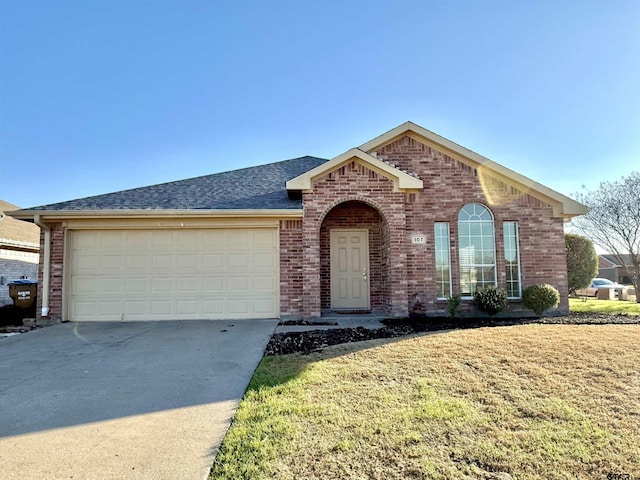 view of front of home with driveway, brick siding, roof with shingles, an attached garage, and a front yard