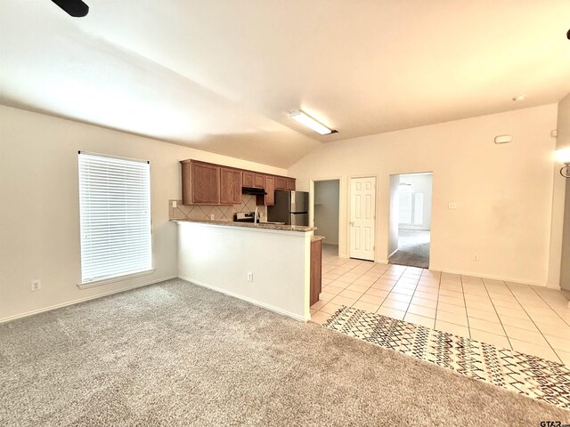 kitchen with sink, backsplash, light tile patterned flooring, vaulted ceiling, and kitchen peninsula