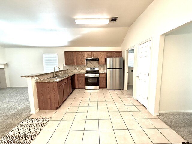 kitchen featuring light tile patterned flooring, lofted ceiling, sink, stone counters, and backsplash