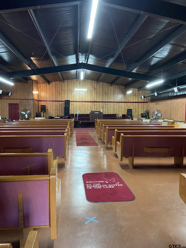 misc room with wood walls, concrete flooring, and vaulted ceiling