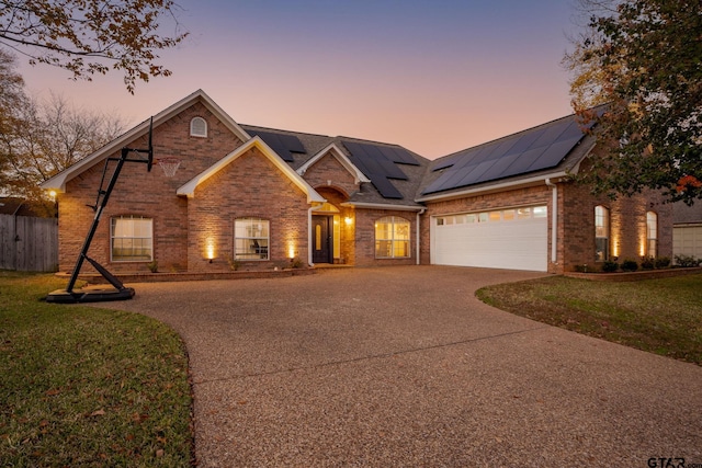 view of front of house with solar panels, a lawn, and a garage