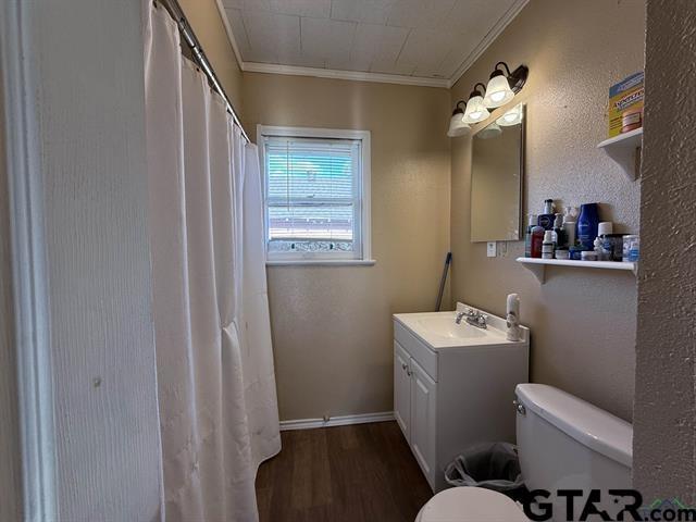 bathroom featuring a shower with curtain, toilet, vanity, crown molding, and wood finished floors