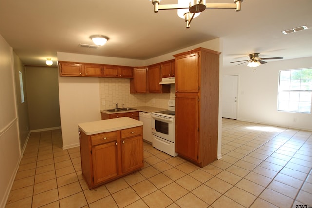 kitchen featuring sink, tasteful backsplash, light tile patterned floors, white appliances, and a center island