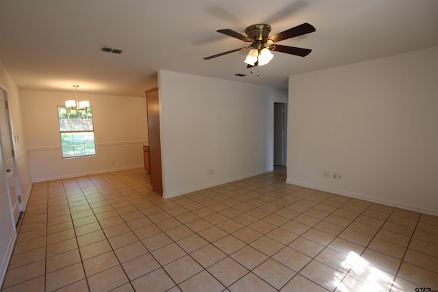 tiled empty room with ceiling fan with notable chandelier