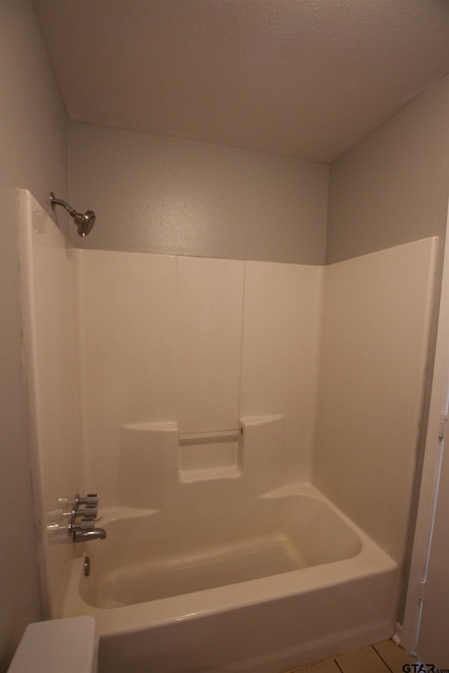 bathroom with shower / bathtub combination, a textured ceiling, and tile patterned flooring