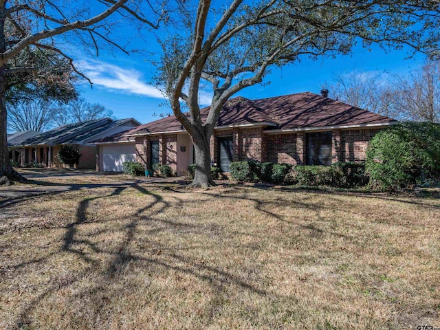 single story home with an attached garage, a front lawn, and brick siding