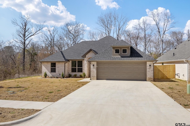 view of front of house with a front lawn, roof with shingles, driveway, and an attached garage