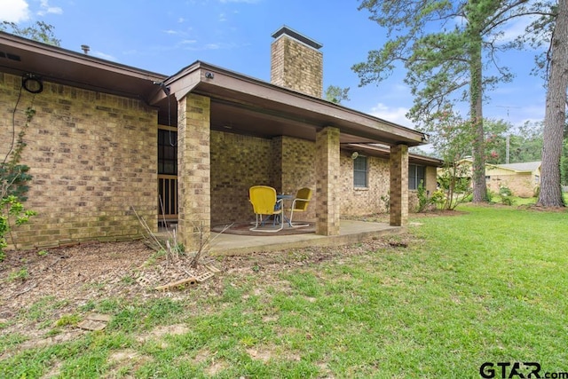 10516 Debbie Ln, Flint, TX 75762 - back of house featuring a patio, a chimney, a yard, and brick siding