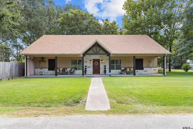 view of front of property featuring stone siding, a front lawn, board and batten siding, and roof with shingles