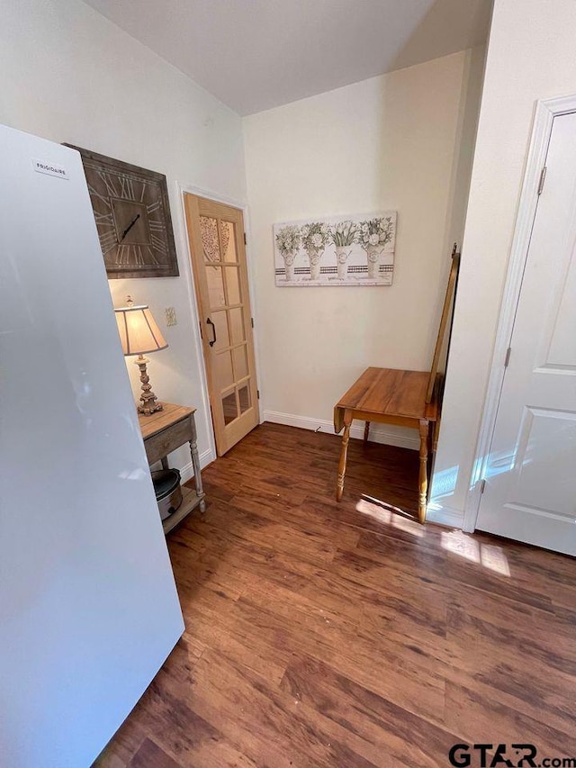 corridor featuring baseboards and wood finished floors