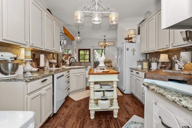 kitchen featuring white appliances, a sink, wall chimney range hood, a chandelier, and backsplash