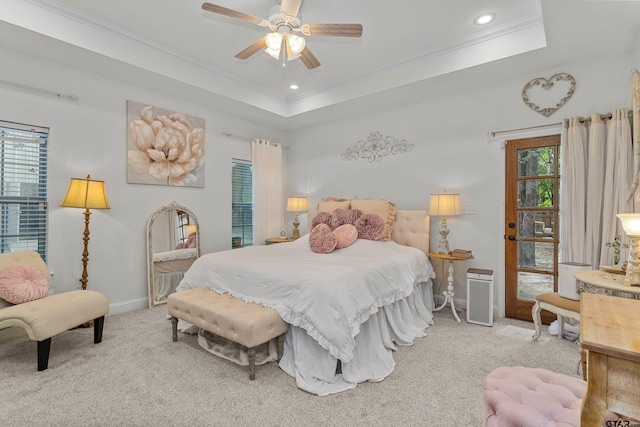 carpeted bedroom with baseboards, a tray ceiling, multiple windows, and crown molding