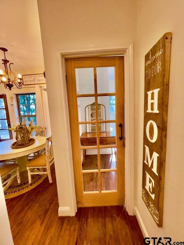 entryway with a notable chandelier, dark wood finished floors, and baseboards