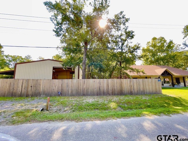 view of side of property with an outbuilding, fence, and a lawn