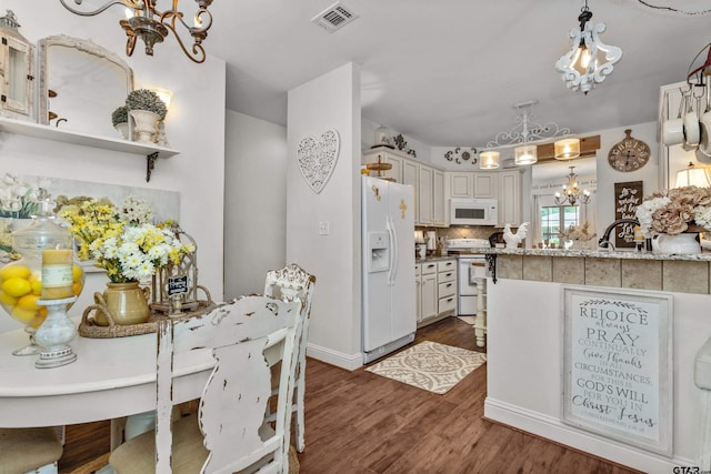 kitchen with a notable chandelier, white appliances, visible vents, tasteful backsplash, and dark wood finished floors