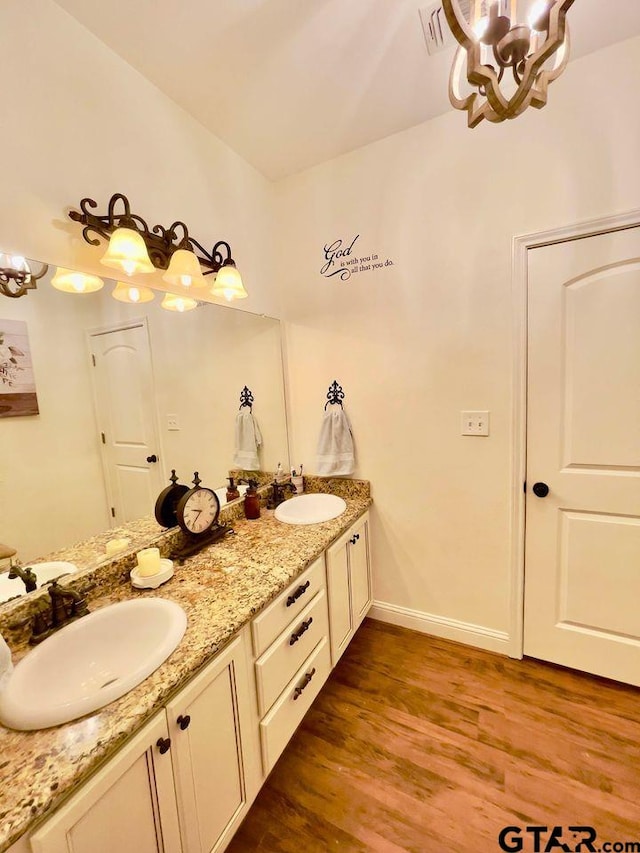 bathroom featuring wood finished floors, a sink, and an inviting chandelier