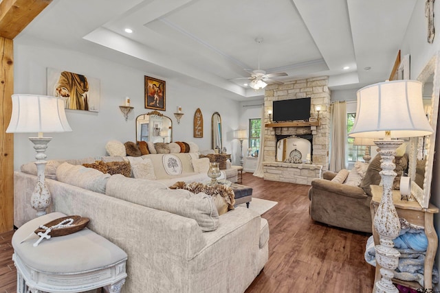 living area with a tray ceiling, a fireplace, recessed lighting, ceiling fan, and wood finished floors