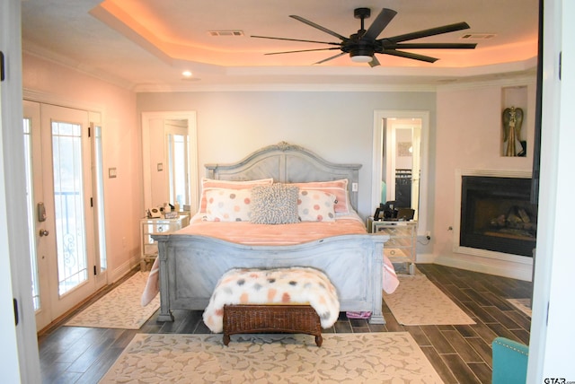 bedroom featuring ornamental molding, a tray ceiling, dark wood-type flooring, and visible vents