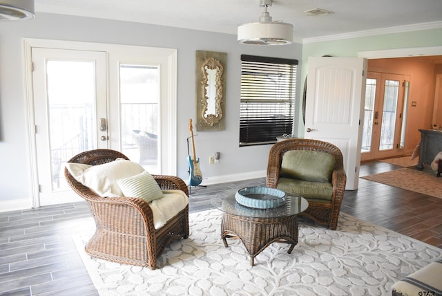 living area with french doors, visible vents, crown molding, wood finished floors, and baseboards