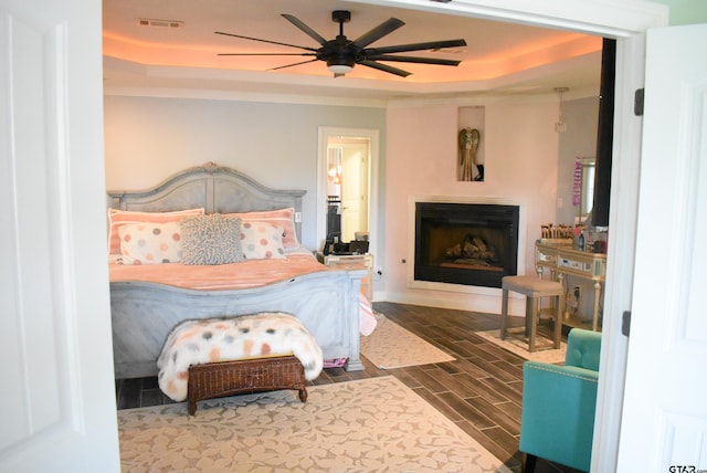 bedroom featuring wood tiled floor, visible vents, crown molding, a fireplace, and a tray ceiling