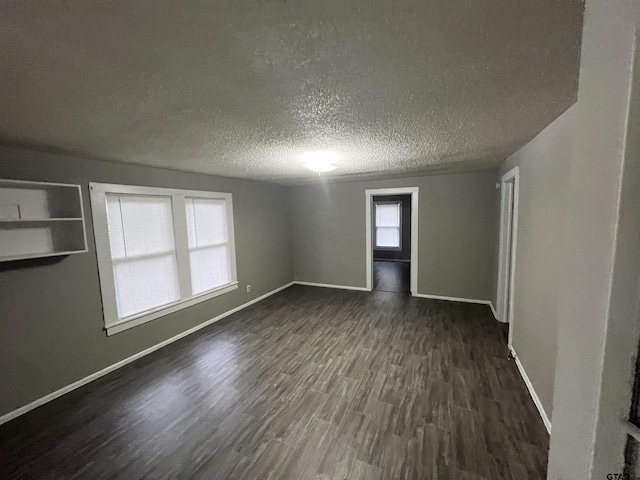 empty room with dark wood-type flooring, baseboards, and a textured ceiling