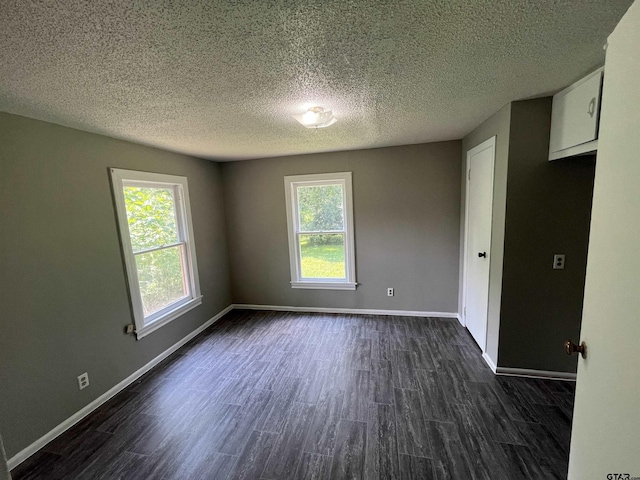 spare room featuring a textured ceiling, baseboards, and dark wood-style flooring