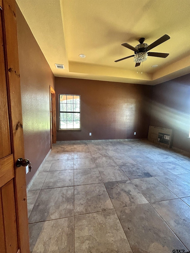 spare room with ceiling fan and a raised ceiling