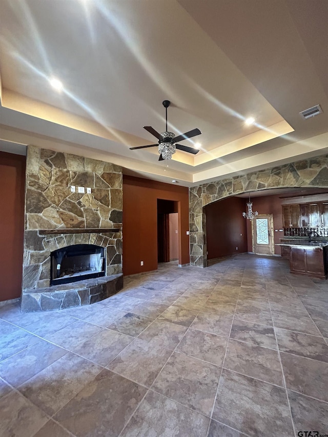 unfurnished living room with ceiling fan, a fireplace, and a tray ceiling